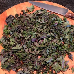 Finely chopped kale on the cutting board with a chef's knife..