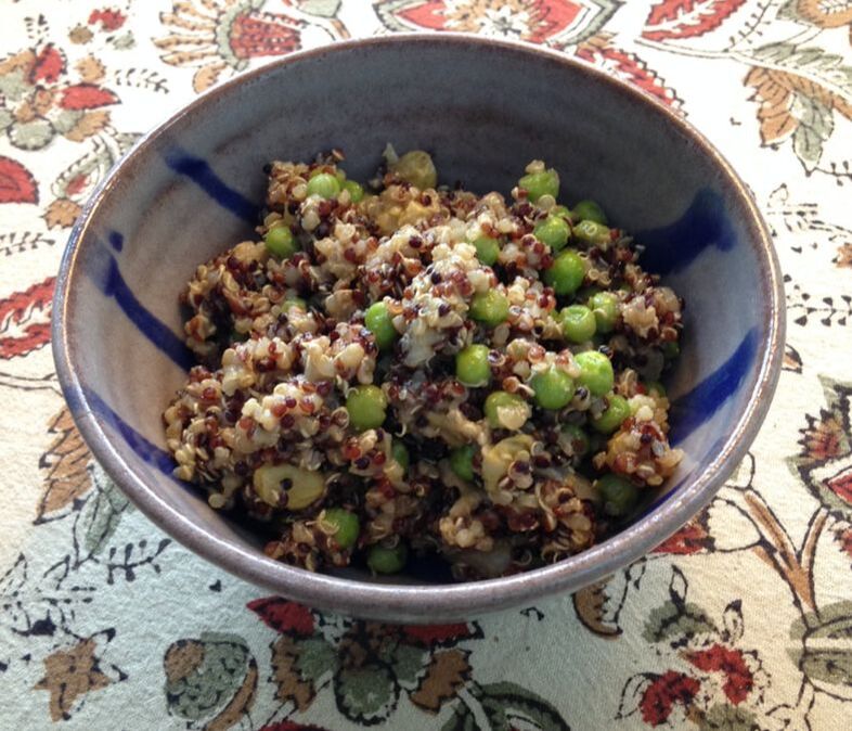 Curried Quinoa with green peas in a small serving bowl.