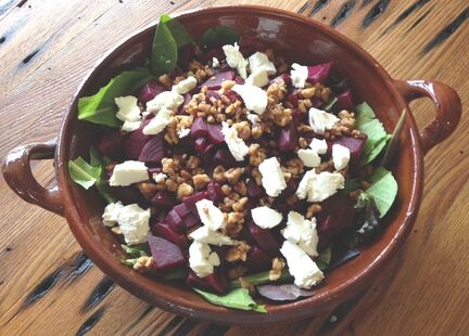 Beet chunks on a bed of spinach with goat cheese and pecans. This salad is in a bowl from Barcelona, Spain.